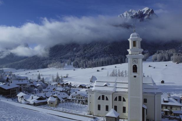 Imagen invernal de Sesto con la iglesia en primer plano, en Dolomitas